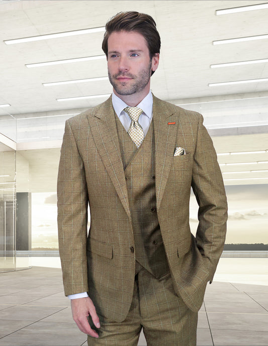 A man with light brown hair and beard wears the Statement Clothing MONTE-TAN Italian wool suit with peak lapels, paired with a white shirt and patterned tie, standing in a bright, modern indoor space.