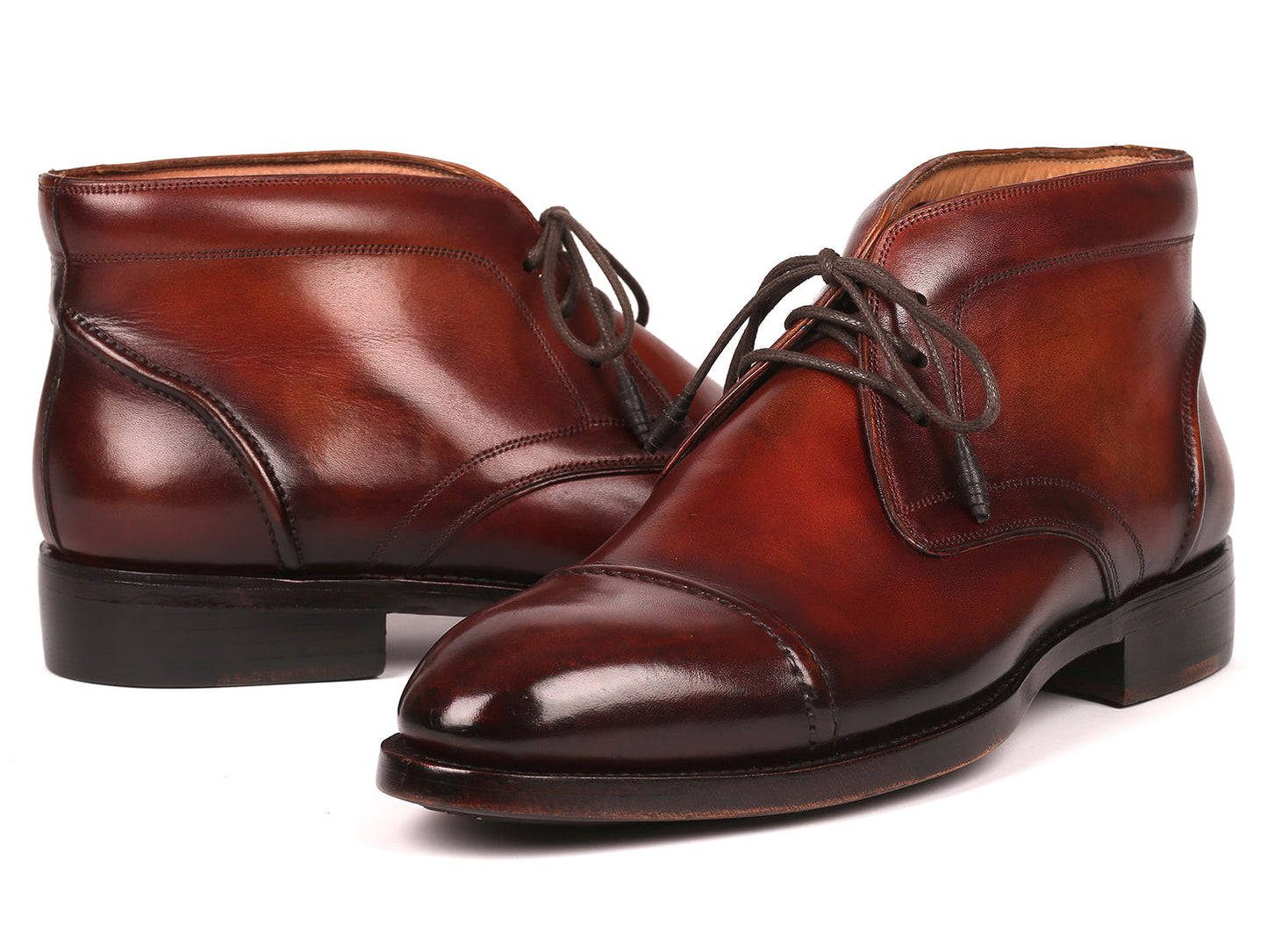 The Paul Parkman Cap Toe Chukka Boots Brown - 144BRW68, polished brown leather dress boots with laces, feature Goodyear welt construction and are displayed on a white background—one upright, the other leaning against it.