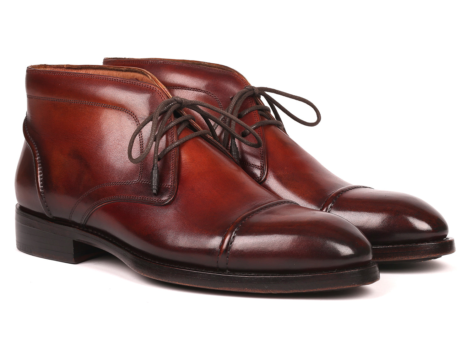 The Paul Parkman Cap Toe Chukka Boots Brown - 144BRW68, polished brown leather dress boots with laces, feature Goodyear welt construction and are displayed on a white background—one upright, the other leaning against it.