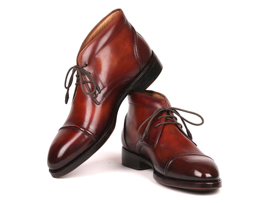 The Paul Parkman Cap Toe Chukka Boots Brown - 144BRW68, polished brown leather dress boots with laces, feature Goodyear welt construction and are displayed on a white background—one upright, the other leaning against it.