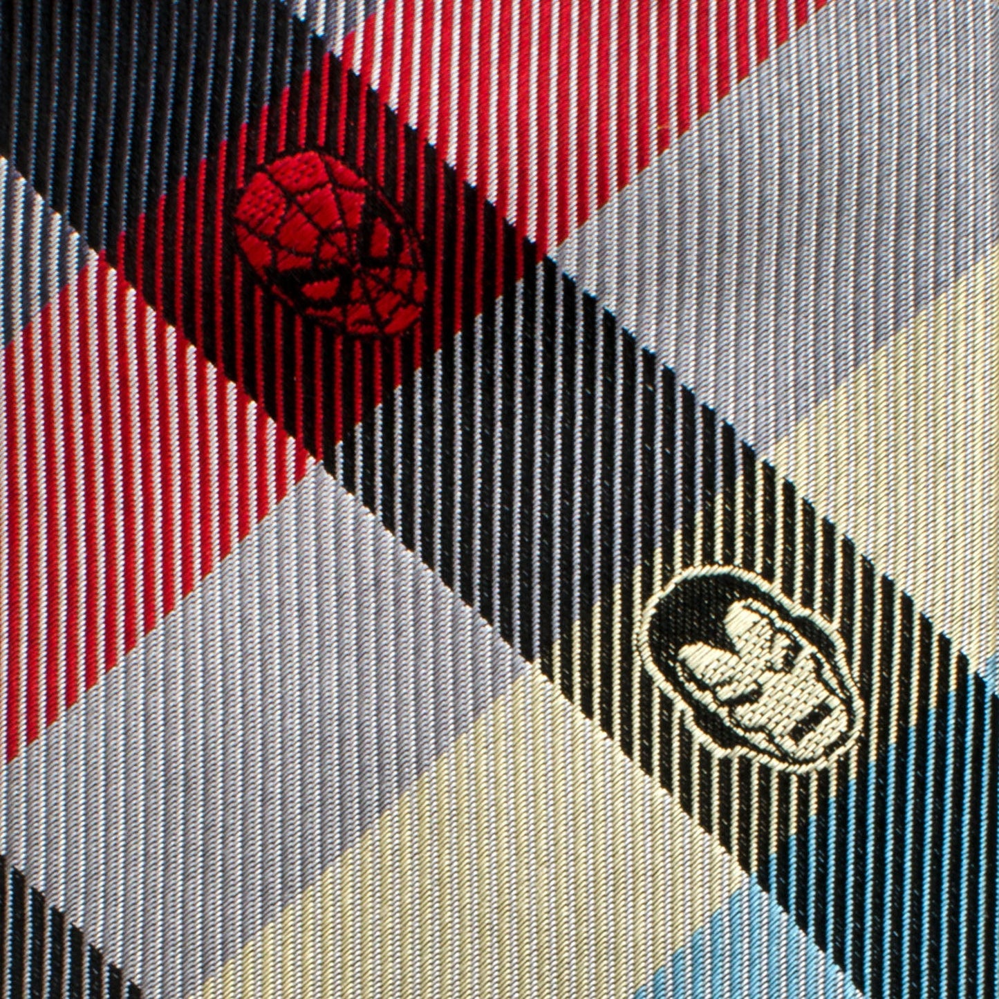 The Marvel Comics Plaid Men's Tie by Cufflinks.com is a rolled-up tie with a light blue, yellow, red, and navy plaid pattern featuring small superhero logos in some sections.