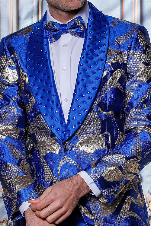 Dressed in the MANZINI MZS-601 Metallic Pattern Rhinestone Tuxedo Suit Royal Jacket, an individual exudes confidence against an ornate backdrop, the suit's shimmering metallic threads beautifully catching the light.