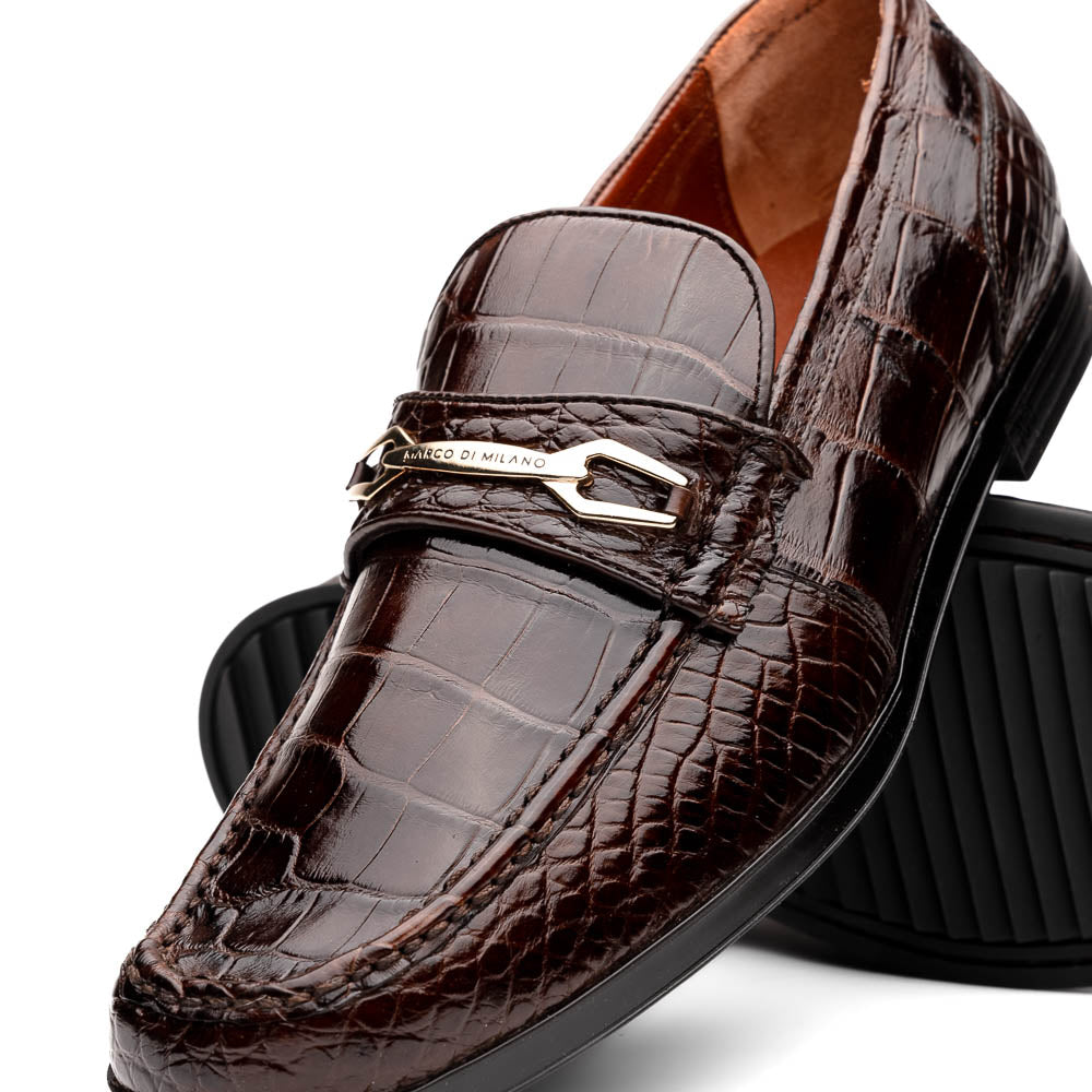 A pair of Marco Di Milano "Milan Brown" luxury loafers featuring brown crocodile-pattern leather and a metal buckle; one shoe is upright while the other is on its side, displaying the sole.