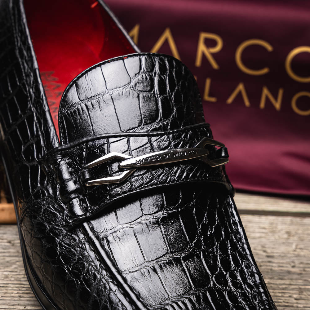 The Milan Black by Marco Di Milano is a black crocodile-pattern leather loafer with a metallic logo detail on the strap and red interior lining, epitomizing luxury men’s footwear.