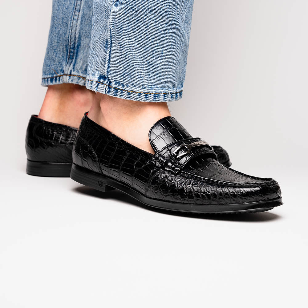The Milan Black by Marco Di Milano is a black crocodile-pattern leather loafer with a metallic logo detail on the strap and red interior lining, epitomizing luxury men’s footwear.