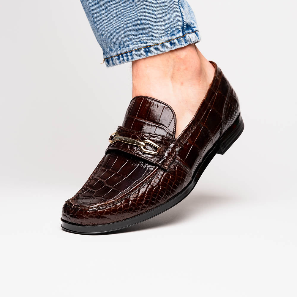 A pair of Marco Di Milano "Milan Brown" luxury loafers featuring brown crocodile-pattern leather and a metal buckle; one shoe is upright while the other is on its side, displaying the sole.