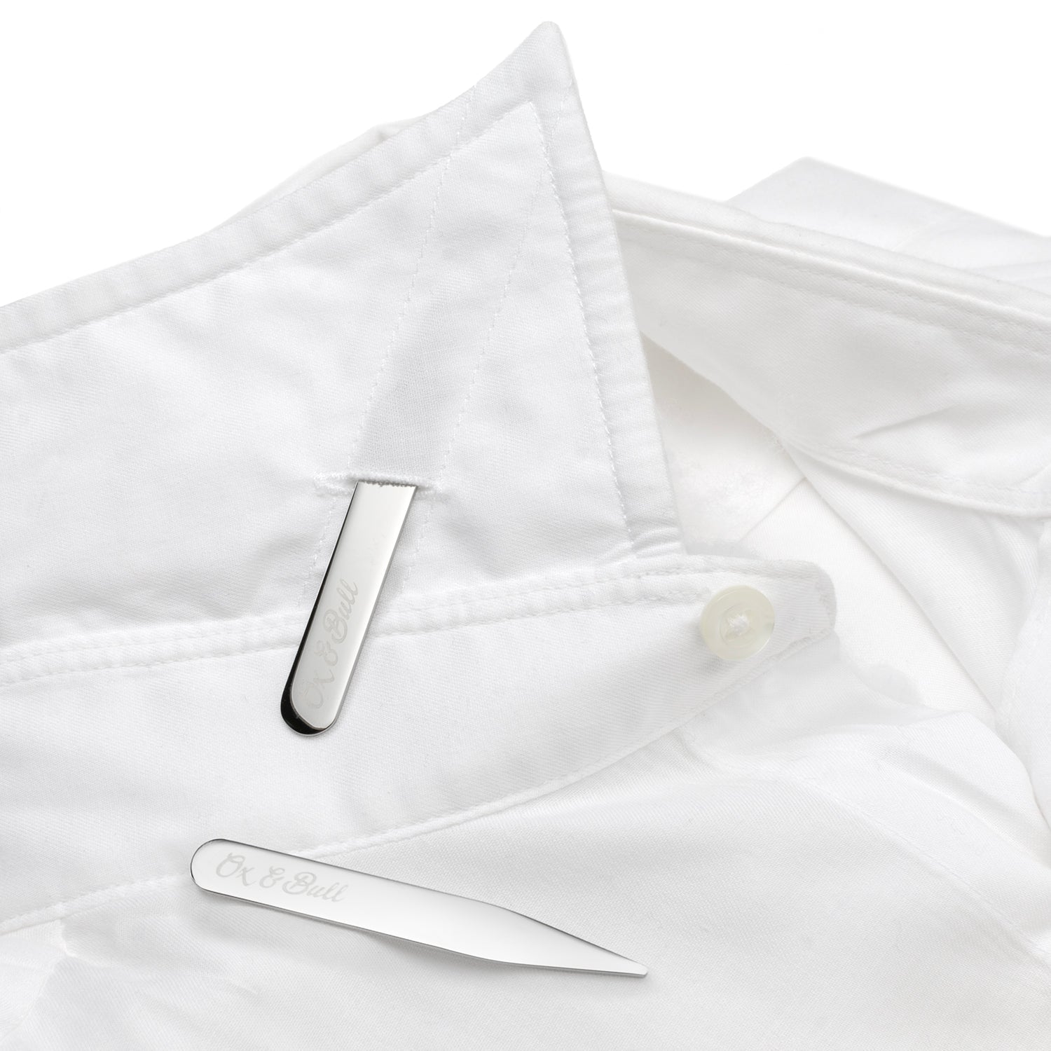 Two Stainless Steel Engravable Collar Stays by Cufflinks.com lie parallel on a white background, adding a sleek, personalized touch to any shirt.
