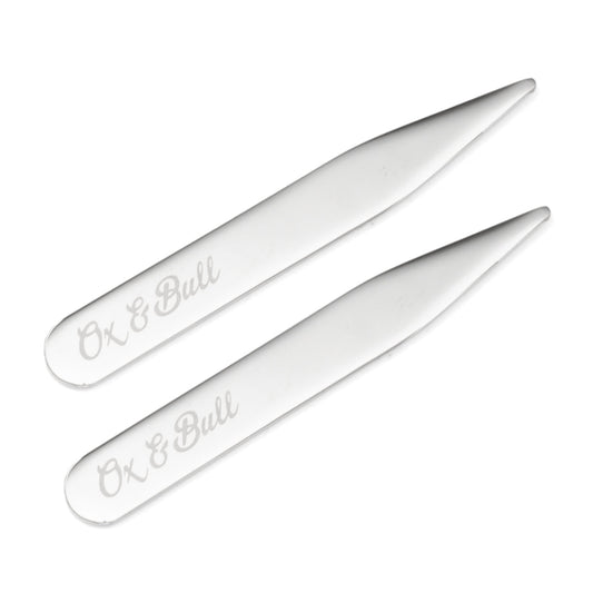 Two Stainless Steel Engravable Collar Stays by Cufflinks.com lie parallel on a white background, adding a sleek, personalized touch to any shirt.