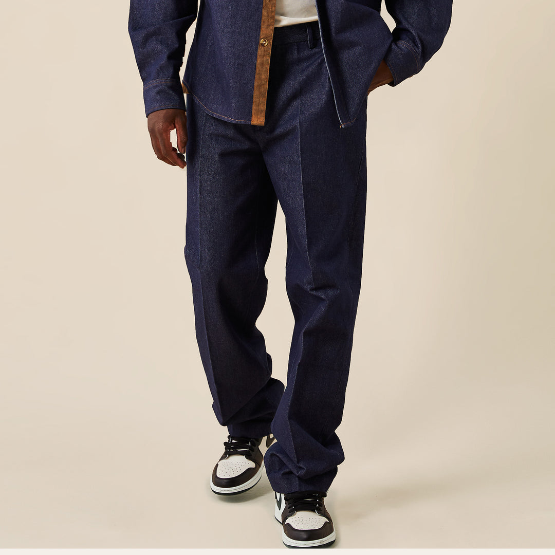 A person wearing Inserch Denim Pants P003-10 Denim Blue with a regular fit dark denim jacket and black and white sneakers, standing against a plain beige background.