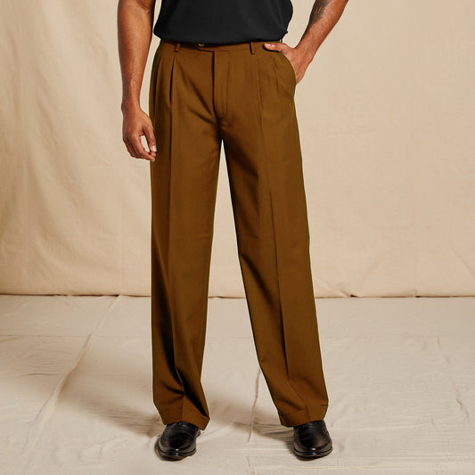 A person wearing Inserch Regular Fit Two Pleat Pants P1199S-27 Aztec stands on a light floor, paired with a black shirt and shoes, against a beige fabric backdrop.