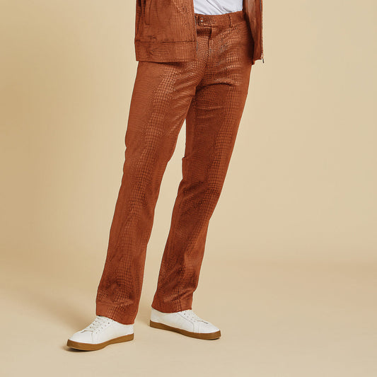 Wearing Inserch Suede Snake Skin Pants P268S-104 Cognac and a matching embossed jacket, white T-shirt, and white sneakers, the person stands against a beige background.