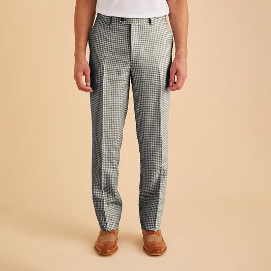 A man confidently walks towards the camera against a plain background, wearing the Inserch Linen Houndstooth Jacket (JS269-00041 Black & White) featuring a sleek 2-way zipper, paired with a black shirt, white pants, and white sneakers.
