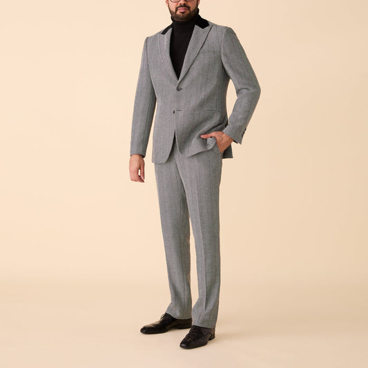 A man wearing the Inserch Herringbone Suit BL273-00041 Black/White by Inserch with a black turtleneck and black shoes stands against a plain beige background.