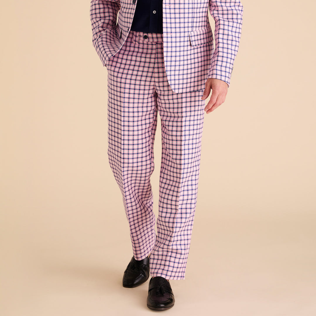 The Inserch Houndstooth Pants P279-00062 for men present a checkered pink and purple design with a 34" inseam, styled as matching bottoms. Featuring a button and zip closure, they lie flat on a beige background, combining comfort with vibrant design effortlessly.