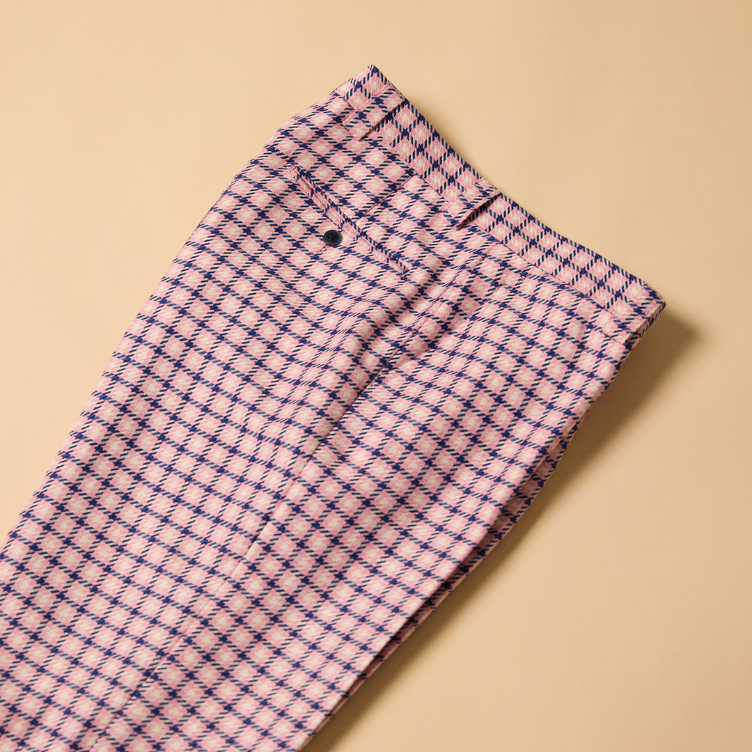 The Inserch Houndstooth Pants P279-00062 for men present a checkered pink and purple design with a 34" inseam, styled as matching bottoms. Featuring a button and zip closure, they lie flat on a beige background, combining comfort with vibrant design effortlessly.