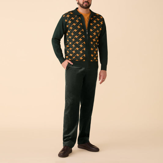 A man stands against a beige background wearing a green and yellow patterned zip-up jacket, mustard shirt, Inserch Cotton Corduroy Pants P3103-21 Hunter Green by Inserch, and brown shoes.