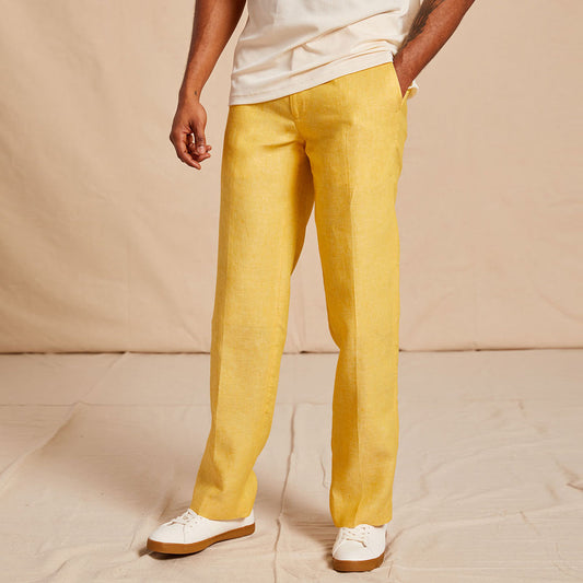 A person wearing a white premium linen shirt and Inserch Linen Pants P3116-00145 Banana Cream by Inserch stands with one hand in pocket against a beige background.