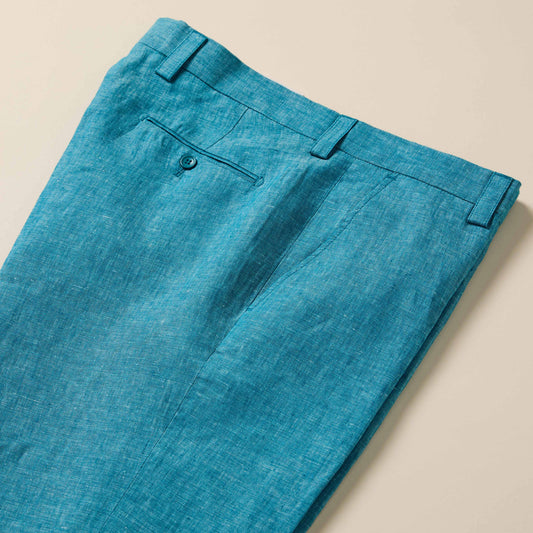 Inserch Linen Pants P3116-00172 Caspian by Inserch: teal blue European flax linen pants with back button pocket, belt loops, and visible seams, shown laid flat on a beige surface.