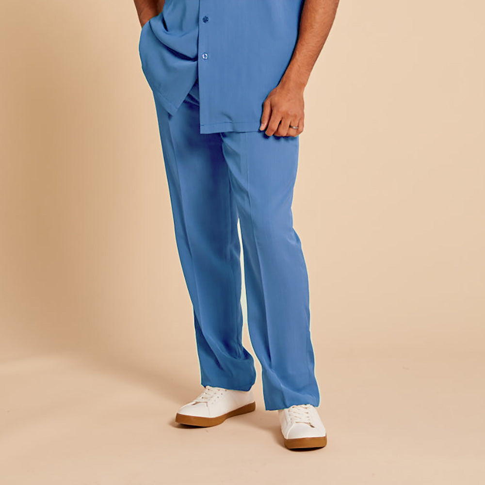 Model wears Inserch Crepe Flat Front Pants P3156-00183 Blue Mist with a blue shirt and white sneakers, posing against a beige background. Made from poly-crepe fabric—easy care, machine wash cold by Inserch.