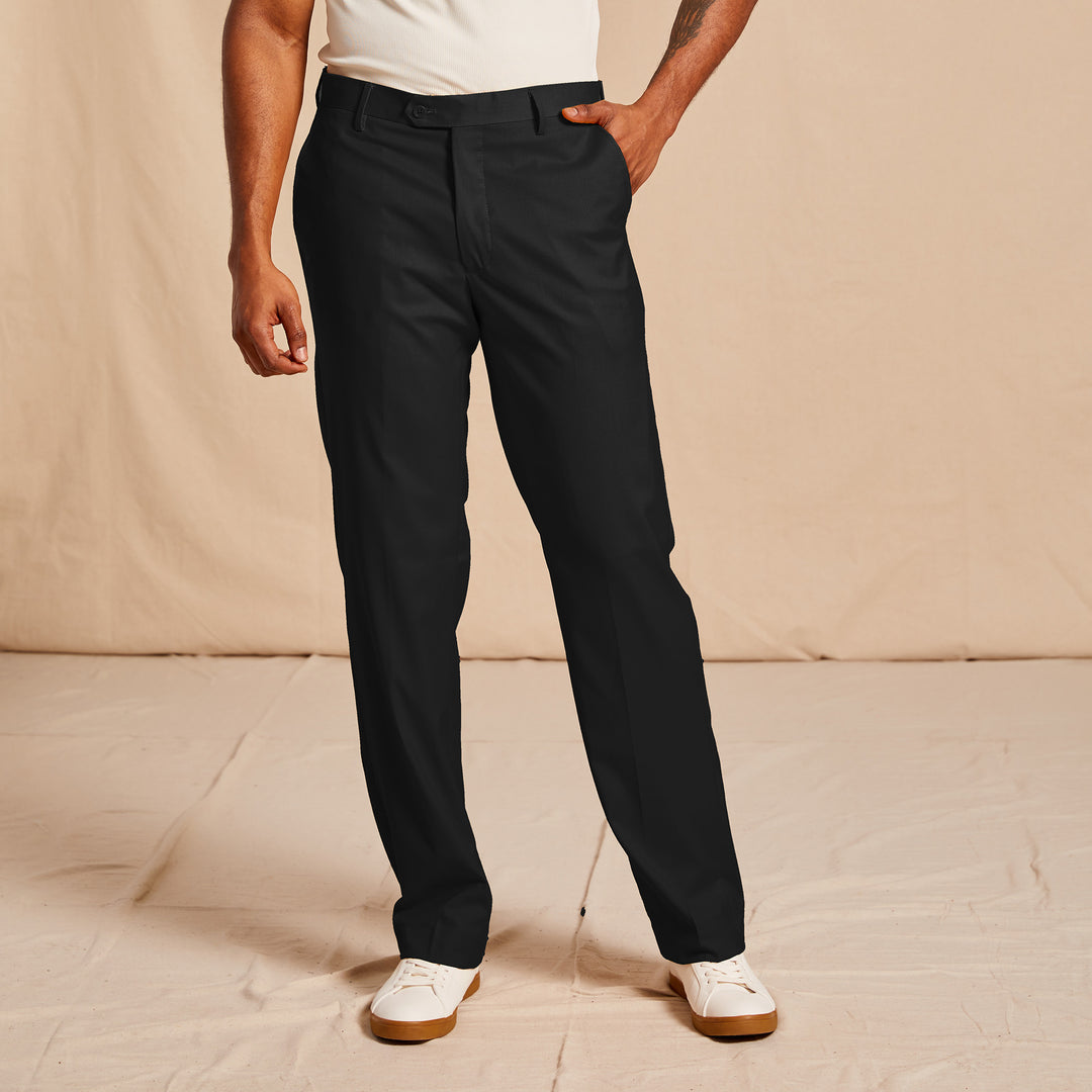 A person wearing Inserch Modern Fit Pants P3199S-01 Black, a white t-shirt, and white sneakers stands with one hand in their pocket against a neutral background.