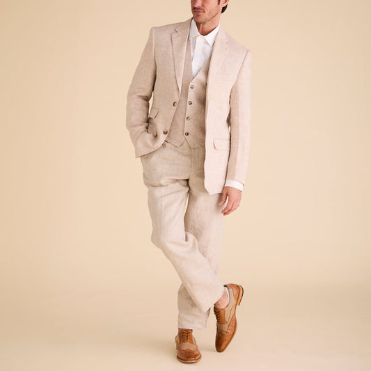 A man wearing Inserch Linen Pants P31-00048 Natural with a matching light beige suit, white dress shirt, and brown dress shoes stands against a neutral background, one leg crossed over the other.