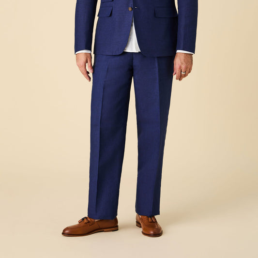 A person in a blue suit with a white shirt, Inserch Linen Pants P31-00150 Summer Navy by Inserch, and brown dress shoes stands against a plain beige background.