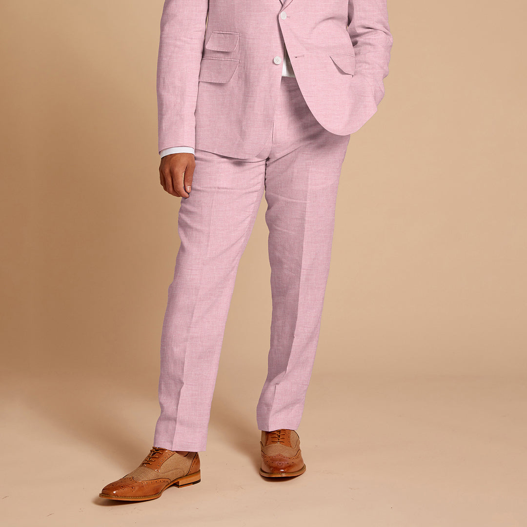 A person confidently poses in Inserch's modern-fit Linen Pants P31-00193 in Desert Rose, made from European flax, against a beige backdrop, styled with fashionable brown shoes.