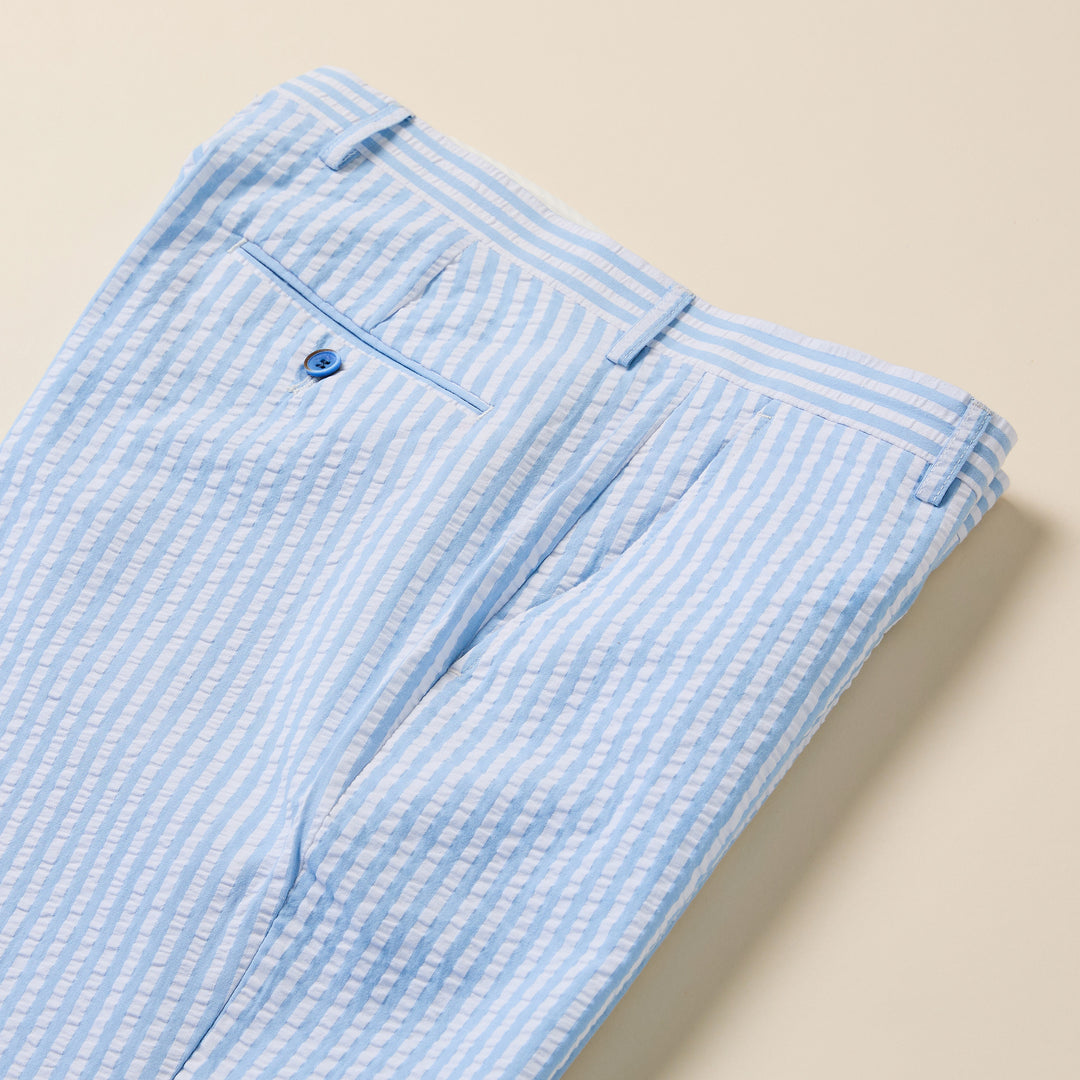The Inserch Seersucker Stripe Pants P660155-00014 in light blue display a modern fit with classic stripes, neatly folded to highlight the back pocket with a blue button and part of the waistband.