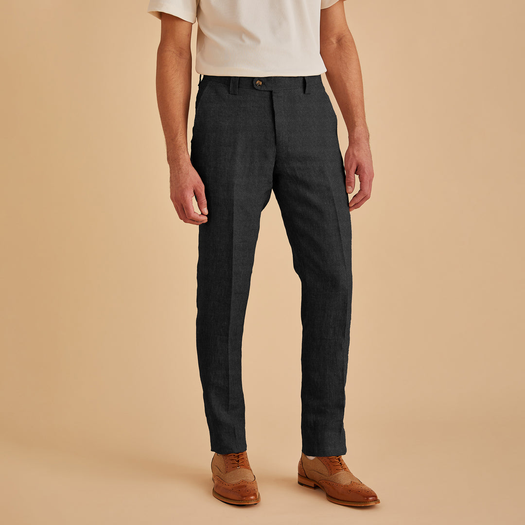 An individual in a white shirt and Inserch Slim Linen Pants P880-00001 Black stands against a beige background, paired with premium brown dress shoes.