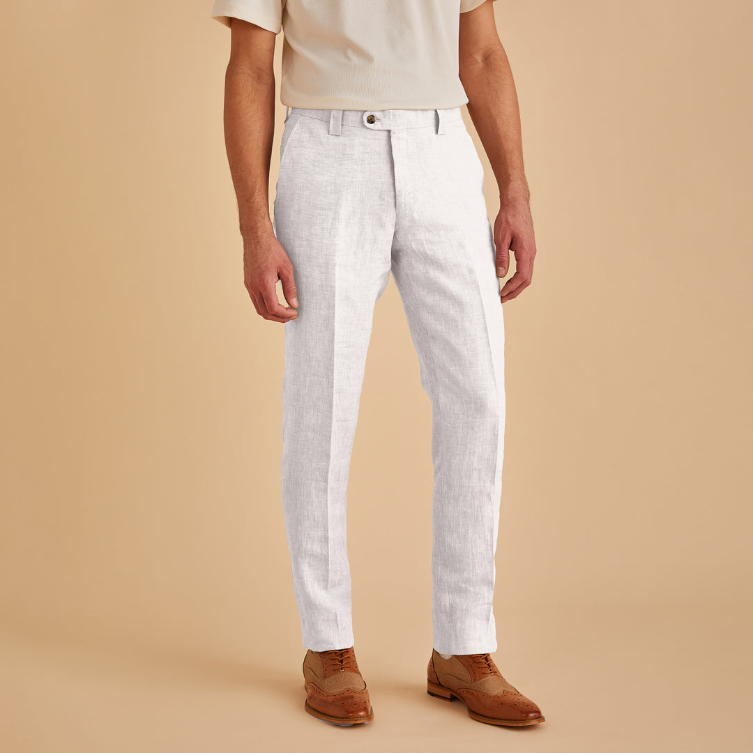 A person in a beige shirt, Inserch Slim Linen Pants P880-00002 White from Inserch, and brown dress shoes stands against a beige background.