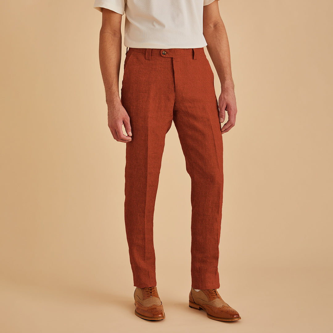 Someone dressed in Inserch Slim Linen Pants P880-00035 Rust, brown dress shoes, and a white shirt stands against a beige backdrop.