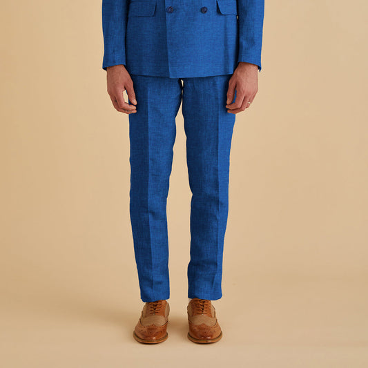 A person wearing Inserch Slim Linen Pants P880-00181 River Blue and brown dress shoes stands against a beige background.