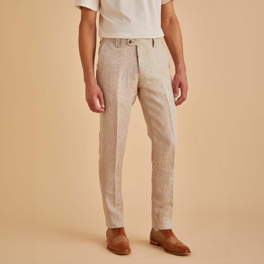 A man poses against a beige background in a white shirt and Inserch Slim Linen Pants P880-06 in Oatmeal. His look is completed with brown dress shoes crafted from premium linen for an elevated style.