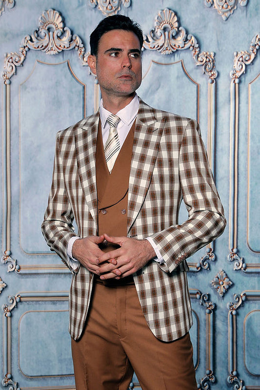 A man wears the Manzini PARIS-4 Men's 3-Piece Tailored-Fit Plaid Business Suit in Coco, featuring a plaid blazer and brown vest, standing before an ornate blue and white paneled wall.