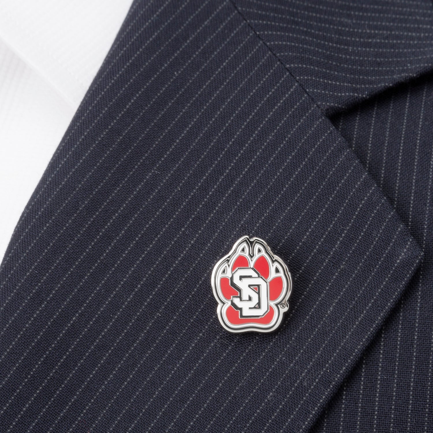 Show your school spirit with the NCAA University of South Dakota Lapel Pin by Cufflinks.com—a red paw print with silver outline and white "SD" letters, perfect for any Coyotes fan or NCAA supporter.