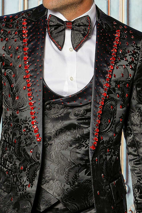A man stands poised against an elegant, floral texture backdrop in a MANZINI PLATINUM 3-Piece Slim Fit Rhinestone Satin Floral Black/Red Tuxedo Suit by Insomnia.