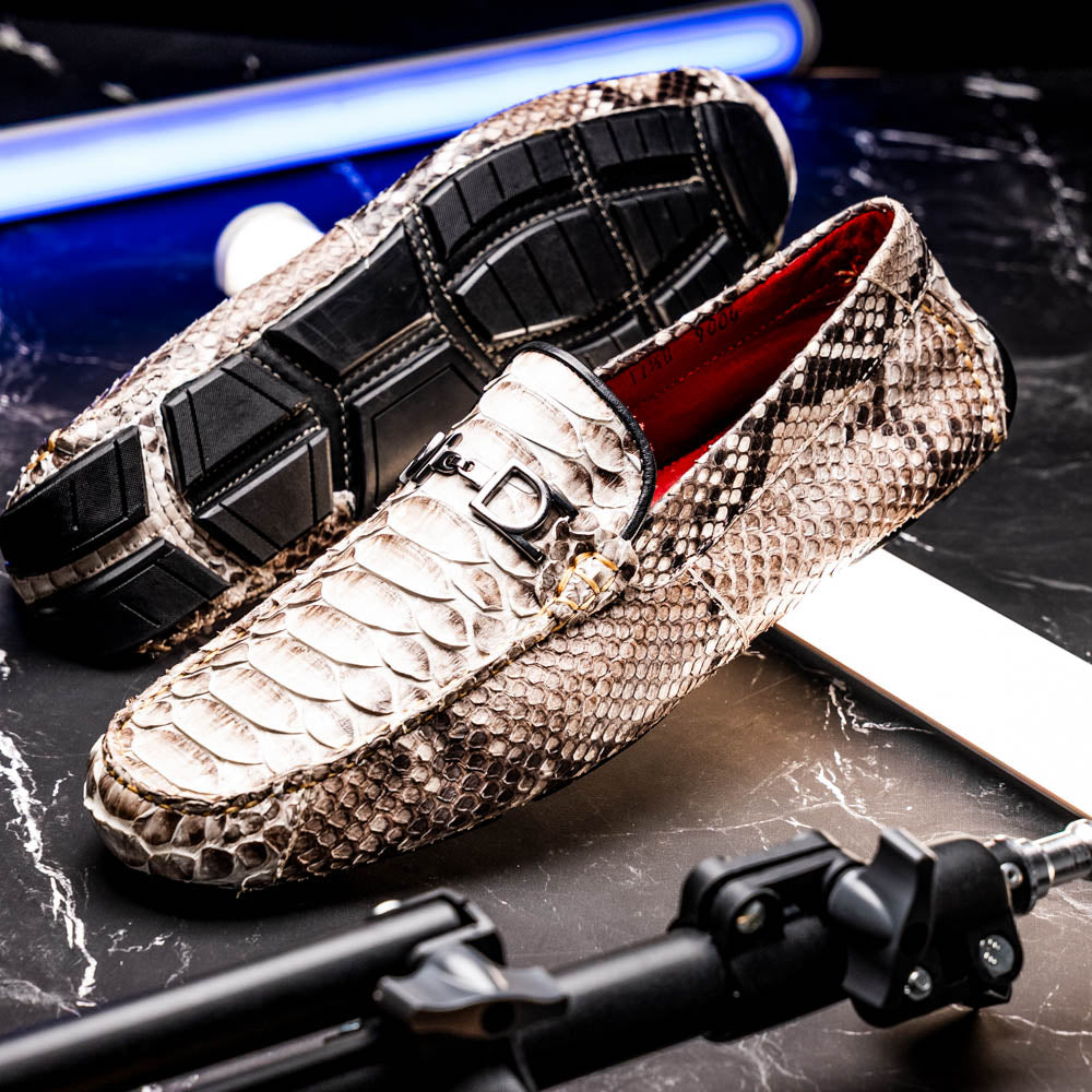 Pair of Marco Di Milano’s Pia Natural men’s loafers, crafted from exotic python skin leather and featuring a sleek metal buckle detail, displayed against a white background. One luxury loafer stands upright while the other is tilted to reveal the sole, showcasing the refined craftsmanship of these signature driver shoes.