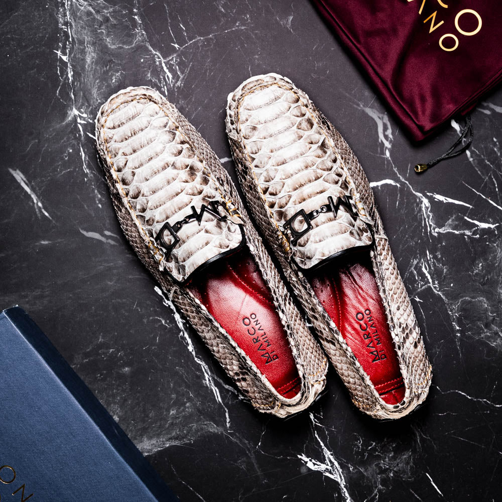 Pair of Marco Di Milano’s Pia Natural men’s loafers, crafted from exotic python skin leather and featuring a sleek metal buckle detail, displayed against a white background. One luxury loafer stands upright while the other is tilted to reveal the sole, showcasing the refined craftsmanship of these signature driver shoes.