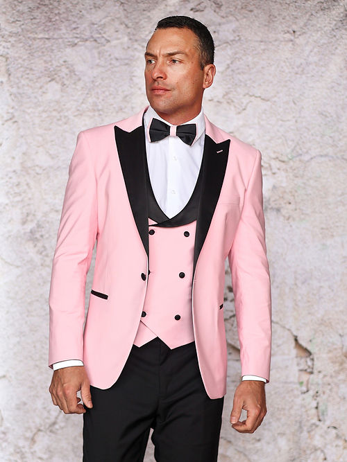 A man in an Insomnia MANZINI ROME Slim Fit 3-Piece Stretch Spandex Pink Tuxedo Suit with black trim and a bow tie stands against a light textured backdrop, highlighting its elegant lines. This dapper ensemble is dry clean only, ensuring it stays pristine for special occasions.