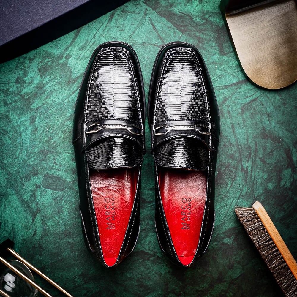 The Ravello Black by Marco Di Milano is a pair of black leather loafers with metal accents, textured uppers, a red interior lining, and ribbed rubber soles—making an exquisite statement in luxury footwear.