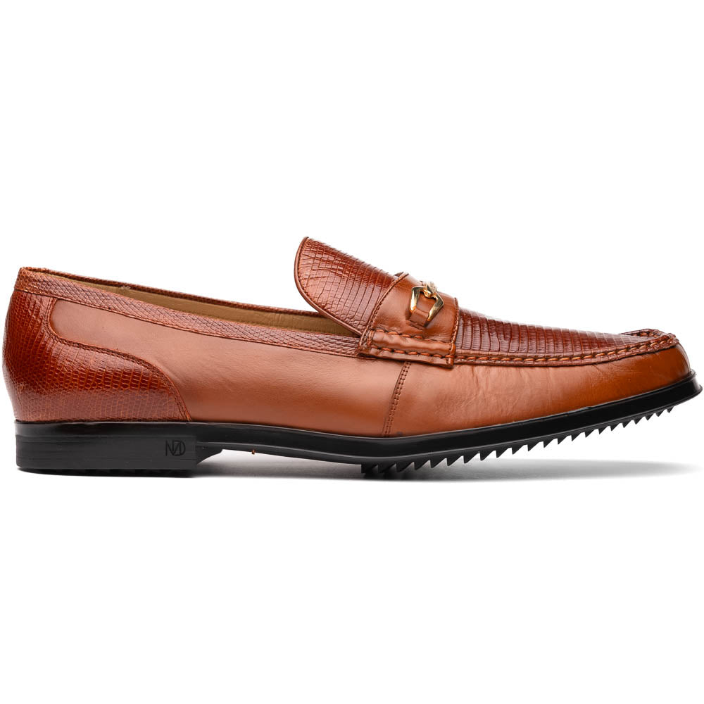 The Marco Di Milano Ravello Cognac loafers feature brown leather with hand-painted finishes and metal detailing; one shoe is upright, while the other displays the black ridged sole.