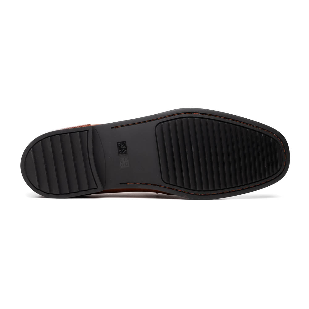 The Marco Di Milano Ravello Cognac loafers feature brown leather with hand-painted finishes and metal detailing; one shoe is upright, while the other displays the black ridged sole.