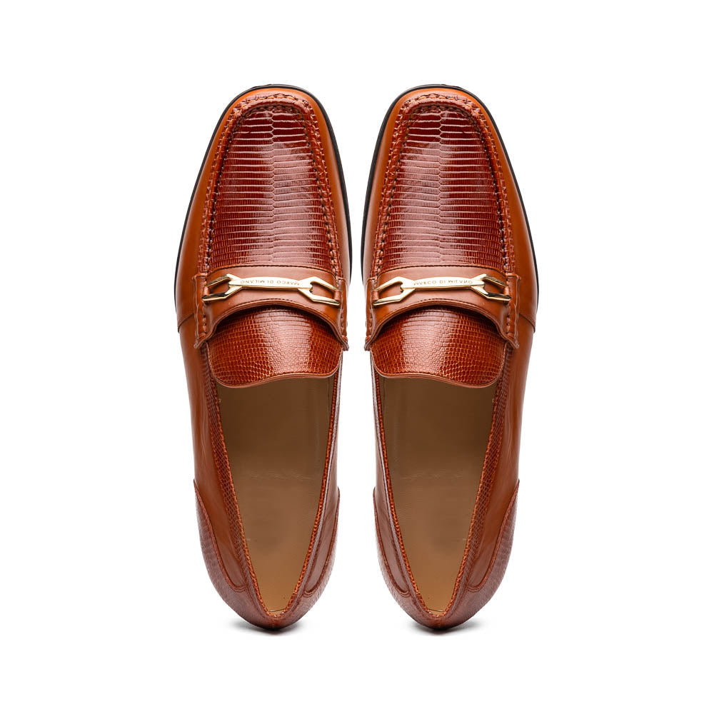The Marco Di Milano Ravello Cognac loafers feature brown leather with hand-painted finishes and metal detailing; one shoe is upright, while the other displays the black ridged sole.