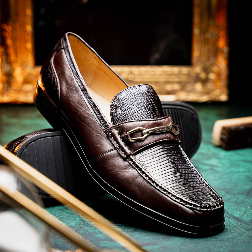 The Marco Di Milano Ravello Brown loafers, crafted from genuine lizard with a metal buckle, are showcased with one shoe upright and the other on its side to highlight the elegant hand-painted finish.