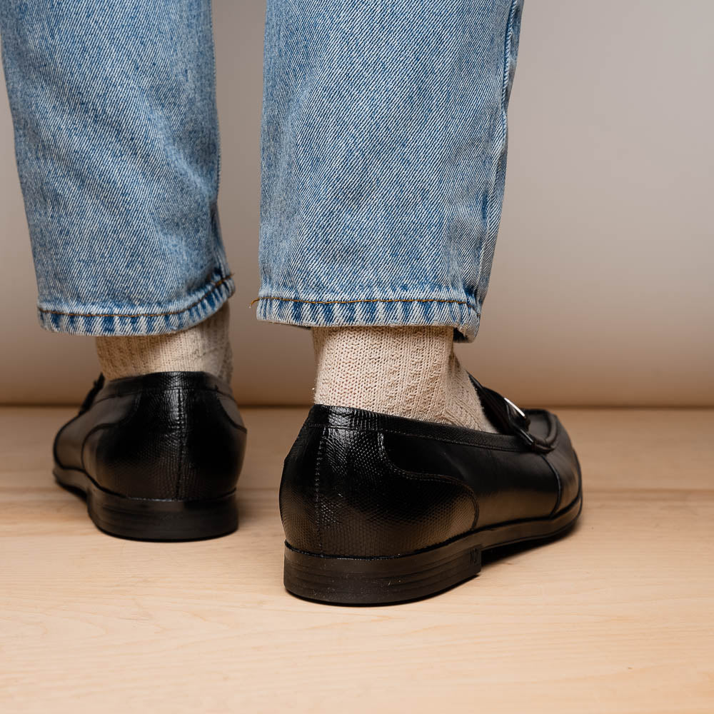 The Ravello Black by Marco Di Milano is a pair of black leather loafers with metal accents, textured uppers, a red interior lining, and ribbed rubber soles—making an exquisite statement in luxury footwear.