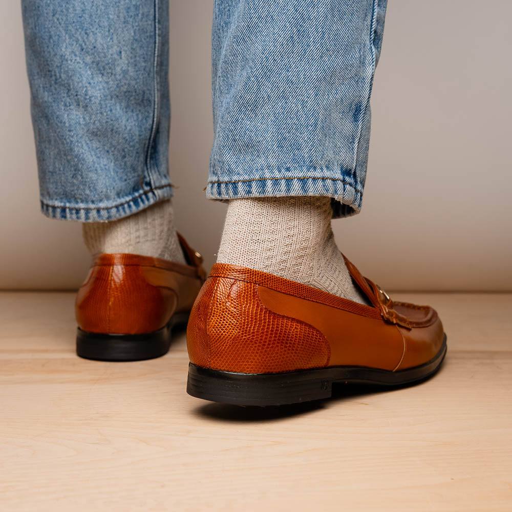 The Marco Di Milano Ravello Honey is a brown leather loafer with a textured finish and metal detail, displayed upright and on its side to show the rubber sole—ideal for those seeking luxury footwear.
