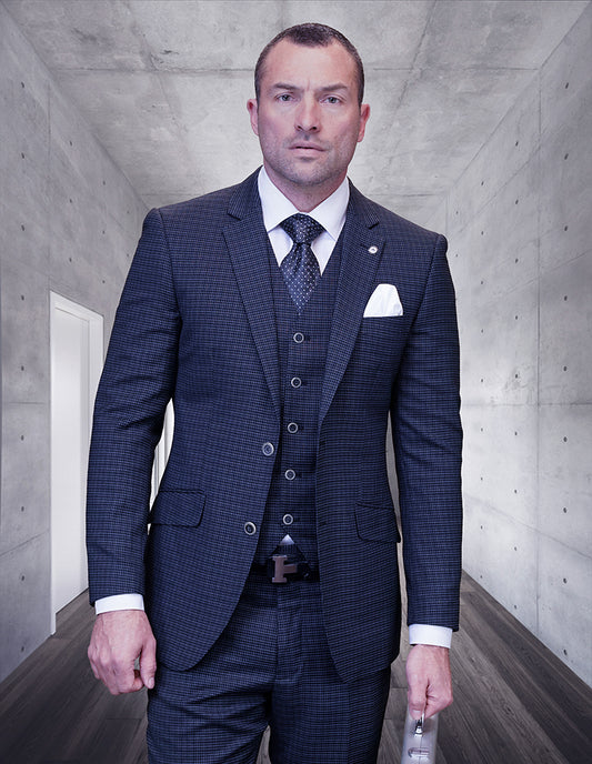 A man in the STATEMENT CLOTHING | SALOTE-BLUE modern fit three-piece suit by Statement Clothing stands in a sleek concrete hallway, holding a briefcase and facing the camera.