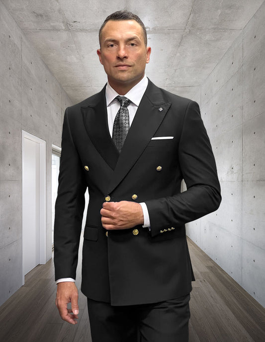 A man wearing the STATEMENT CLOTHING | SD-100-BLACK tailored fit double breasted suit by Statement Clothing, with flat front pants and a tie, stands in a modern hallway with concrete walls and wood flooring.