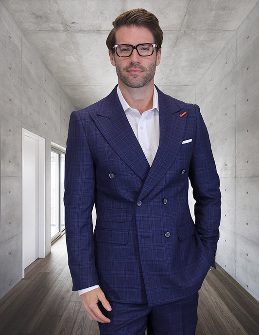 A man in STATEMENT CLOTHING | SD-102-SAPPHIRE by Statement Clothing and glasses stands in a sleek hallway with concrete walls and wooden flooring, looking at the camera.