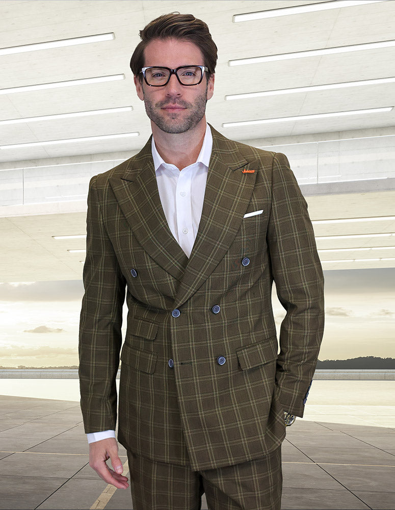 A man wearing glasses and the STATEMENT CLOTHING | SD-103-BROWN modern fit double breasted suit by Statement Clothing stands indoors before large windows with a waterfront view.